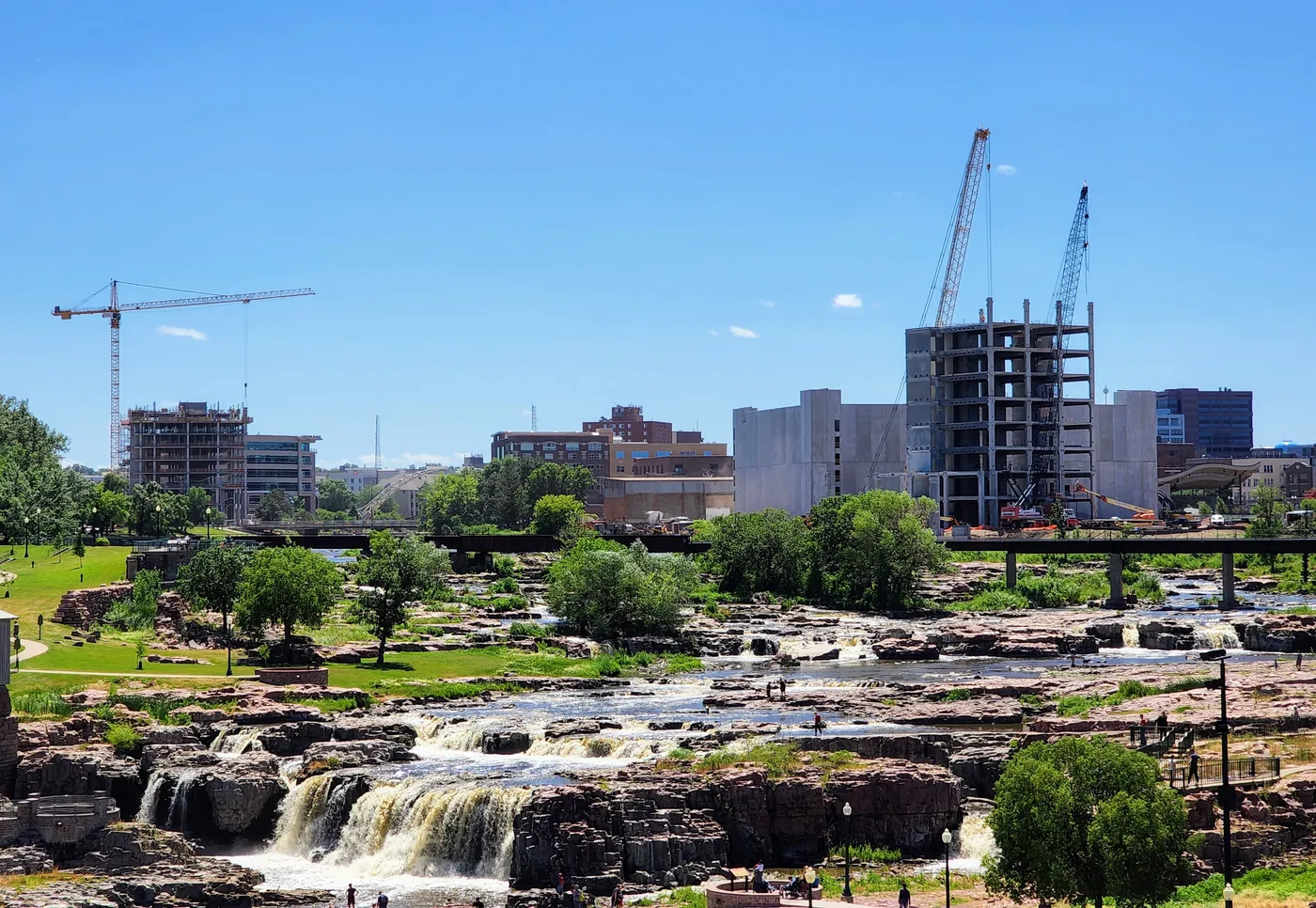 The Big Sioux River cascading over quartzite at Falls Park, with downtown Sioux Falls beyond